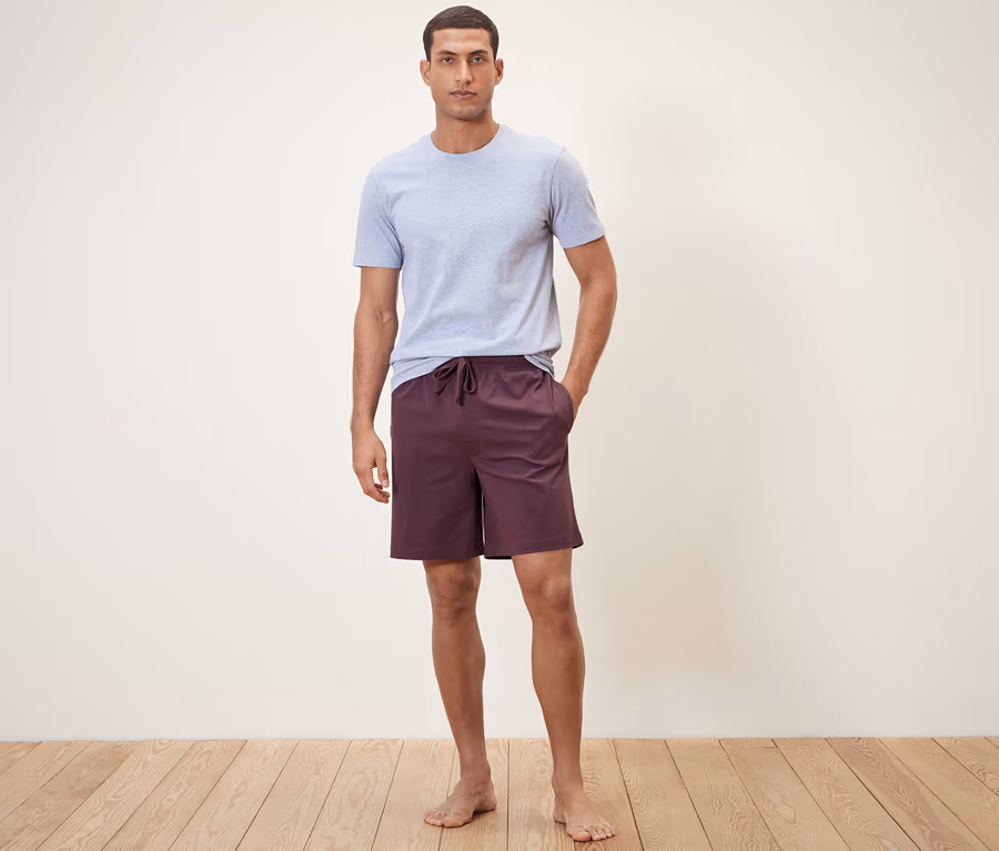 Mann steht und trägt Relaxshorts und ein T-Shirt.