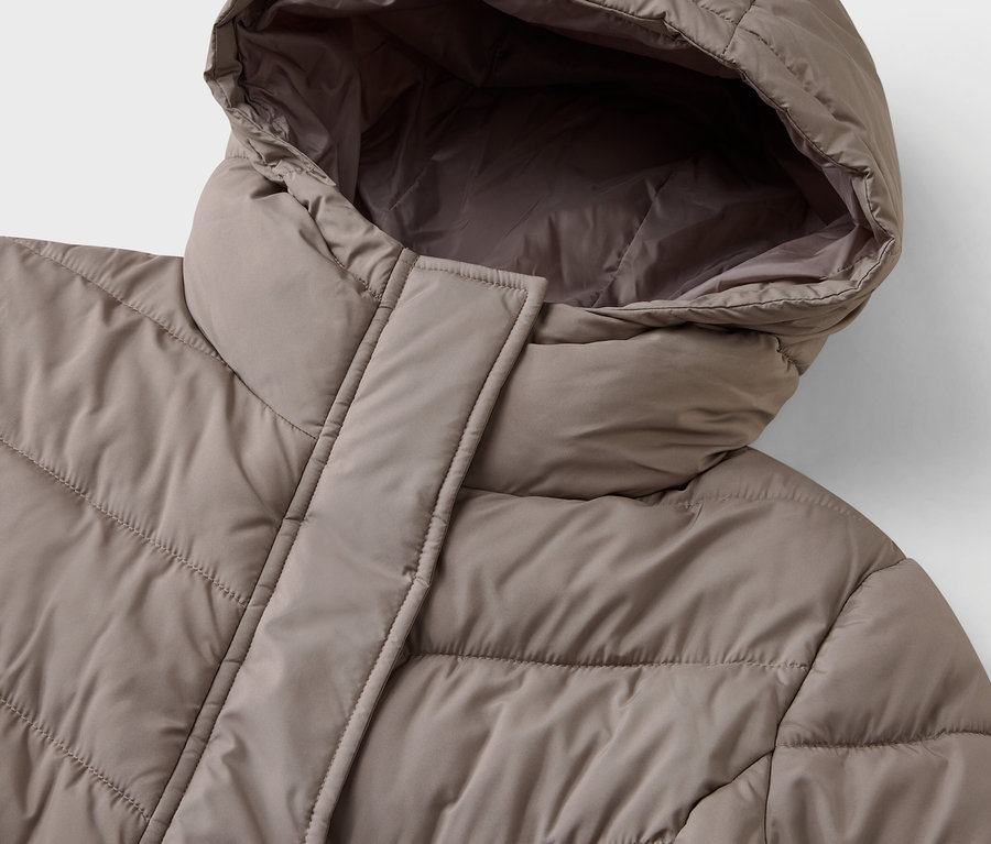 Detailaufnahme einer beigen Steppjacke mit Kapuze.