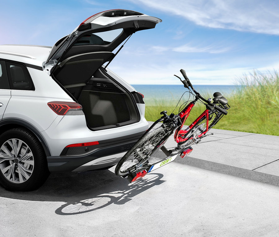 Weißes Auto mit geöffnetem Kofferraum und montiertem EAL Fahrradträger »CROW 1«, auf dem sich zwei Fahrräder befinden.