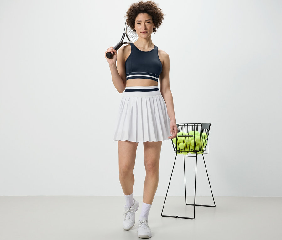 Frau hält Tennisschläger und trägt ein blaues Sport-Bustier »Crop Top«.