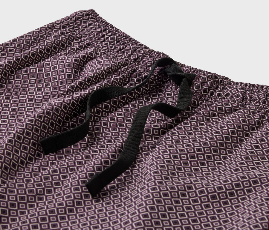 Detailansicht einer lila Pyjamahose mit Muster und schwarzem Kordelzug.
