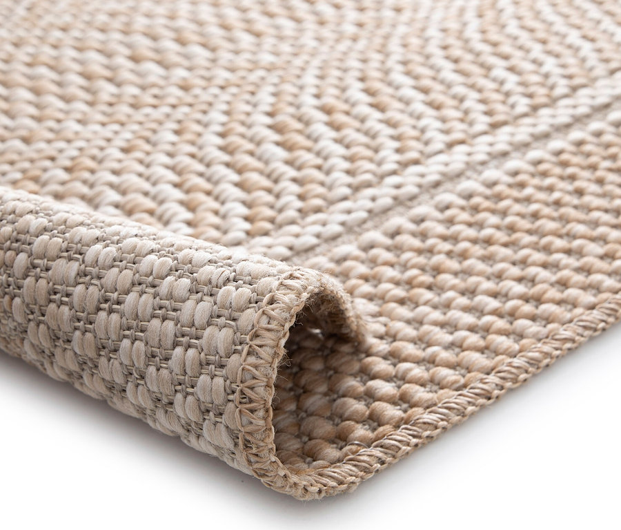 Detailansicht eines beigen Teppichs »Twine« mit Fischgrätenmuster.