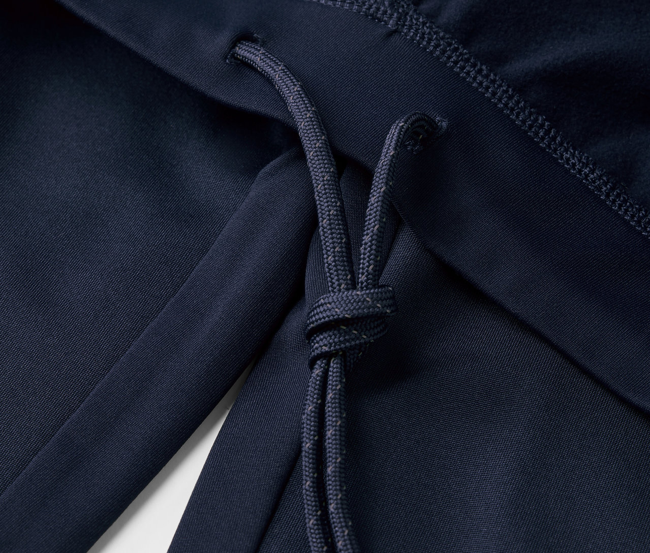 Detailaufnahme einer marineblauen Windprotection-Lauftight mit Kordelzug.