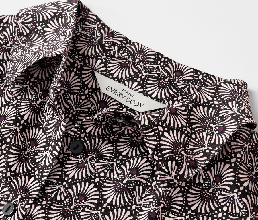 Detailansicht eines Web-Pyjamas mit schwarz-weißem Blumenmuster und Knöpfen.