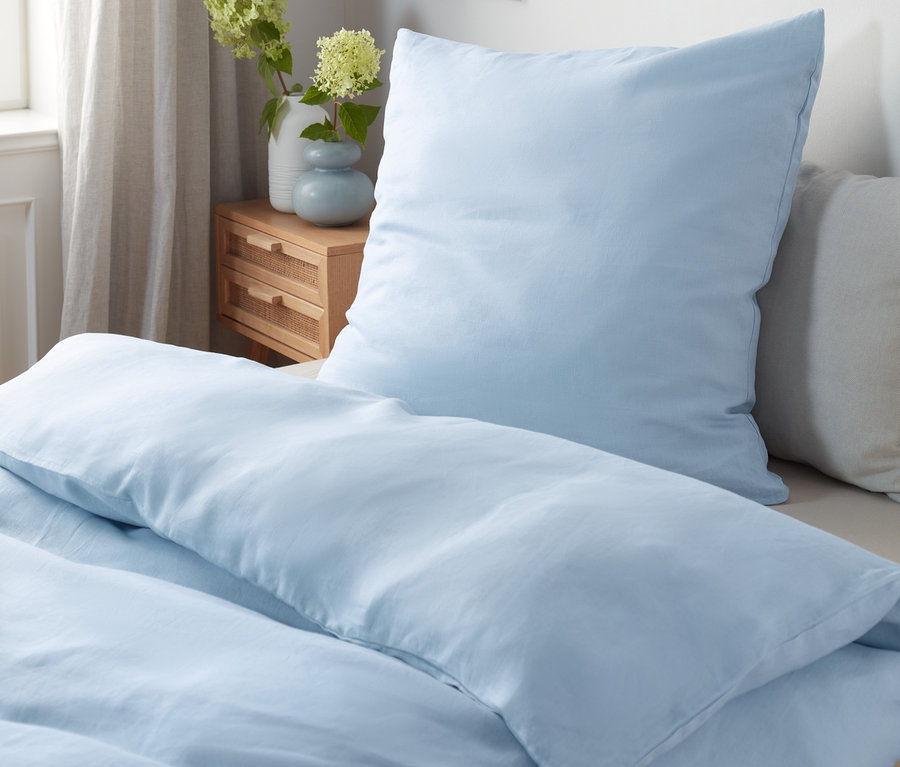 Blaue Leinen-Bettwäsche in Normalgröße und Doppelgröße liegt auf einem Bett.