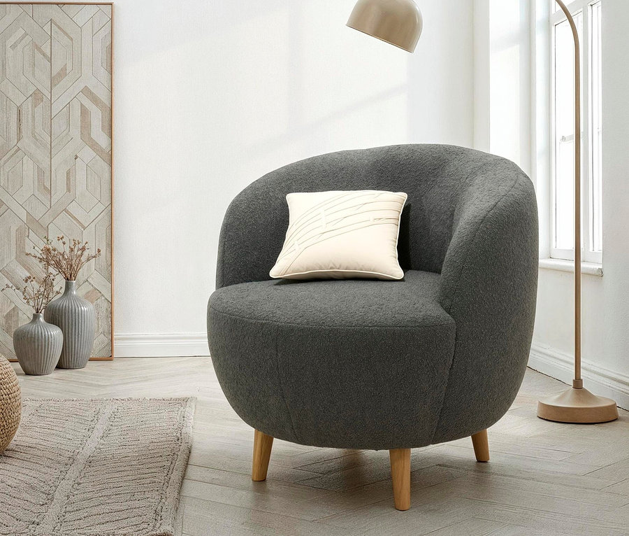 Ein grauer Sessel mit einem cremefarbenen Kissen steht neben einer Bogenlampe.