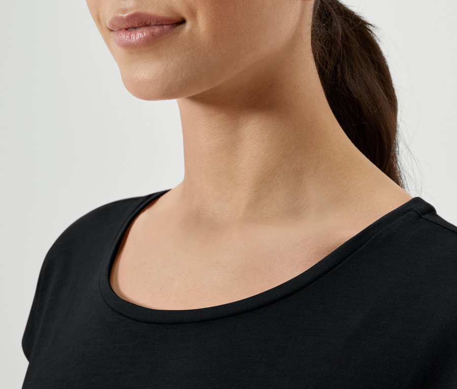 Detailaufnahme einer Frau mit braunen Haaren, die zu einem Pferdeschwanz gebunden sind, die ein schwarzes T-Shirt trägt.