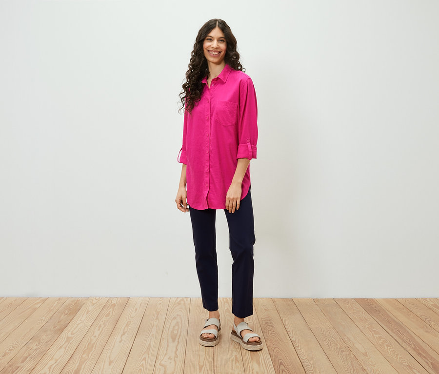 Frau steht und trägt eine lange Leinenbluse, pink.