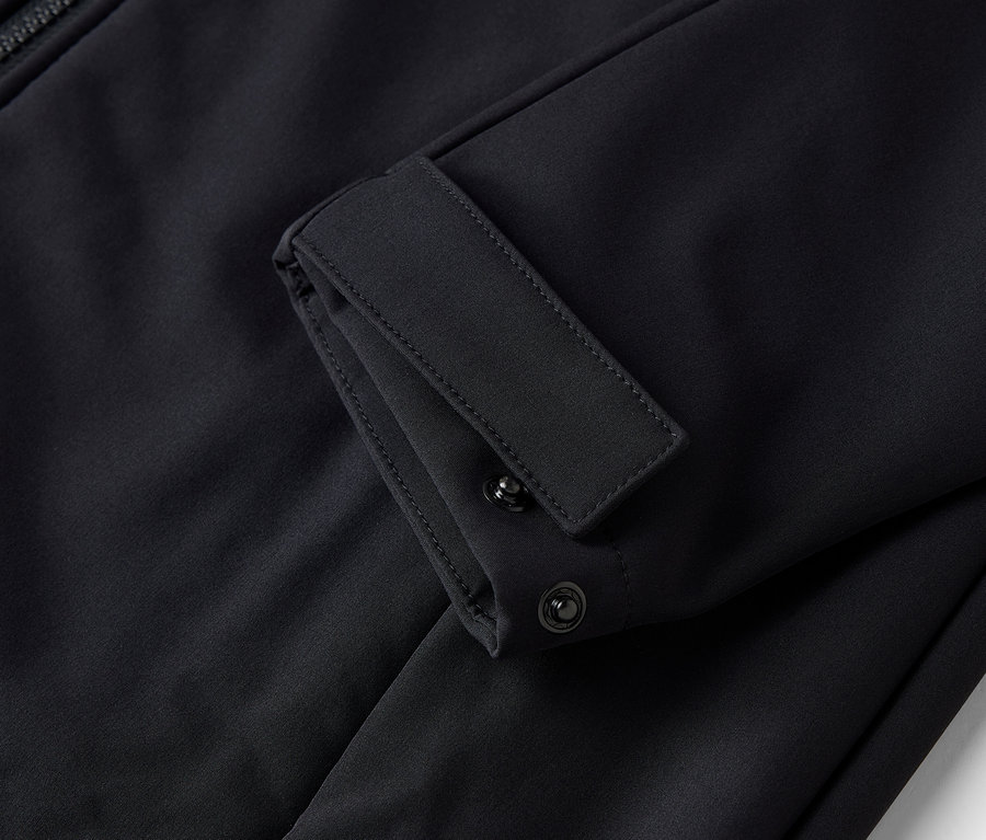 Detailaufnahme einer schwarzen Jacke mit verstellbarer Knopfmanschette.
