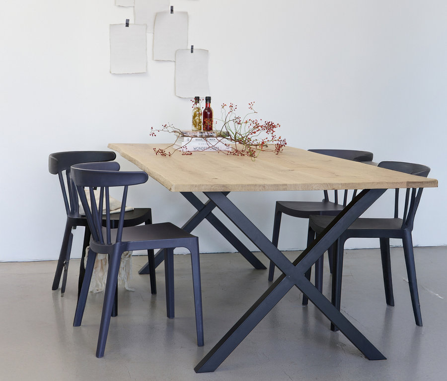 Esstisch aus hellem Holz mit schwarzem X-förmigem Metallgestell und vier schwarzen Stühlen.