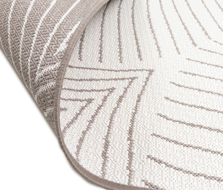 Nahaufnahme eines hellen Teppichs mit abstraktem, grauem Muster und hochgebogener Ecke.