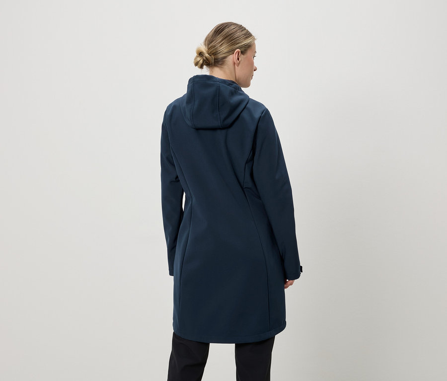 Rückansicht einer Frau mit Dutt, die einen langen, marineblauen Mantel mit Kapuze und schwarze Hosen trägt.