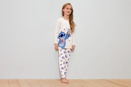 Mädchen trägt einen weißen Schlafanzug mit Stitch-Motiv.