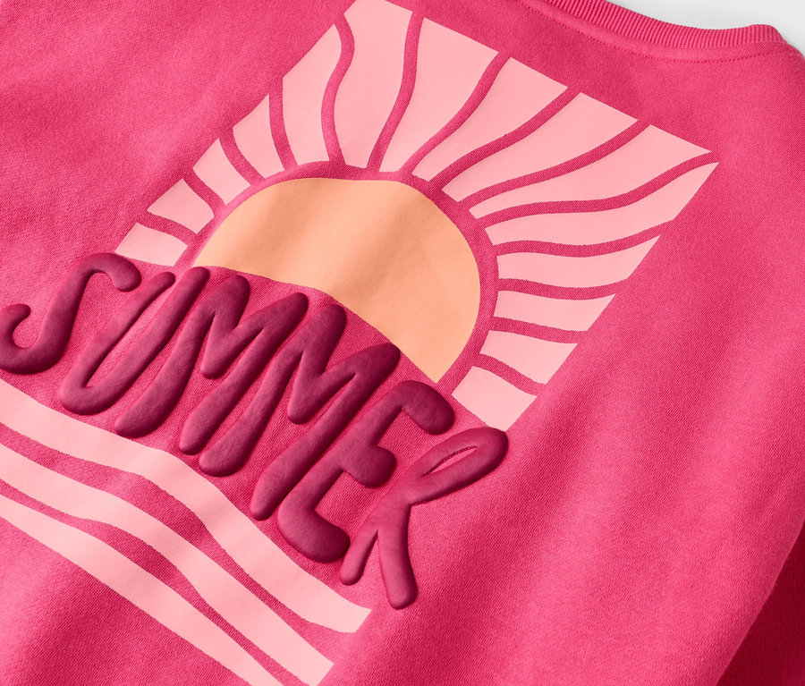 Auf einem pinkfarbenen Pullover ist ein Motiv mit der Aufschrift "SUMMER" und einer Sonne abgebildet.