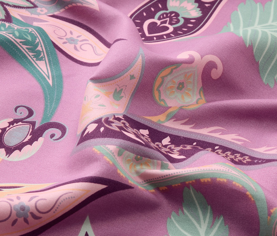 Nahaufnahme eines lila Stoffes mit einem bunten Paisley-Muster.