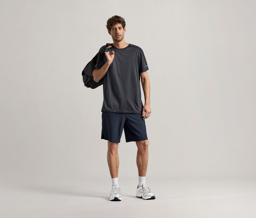 Mann mit anthrazitfarbenem Sportshirt und Sporttasche über der Schulter.