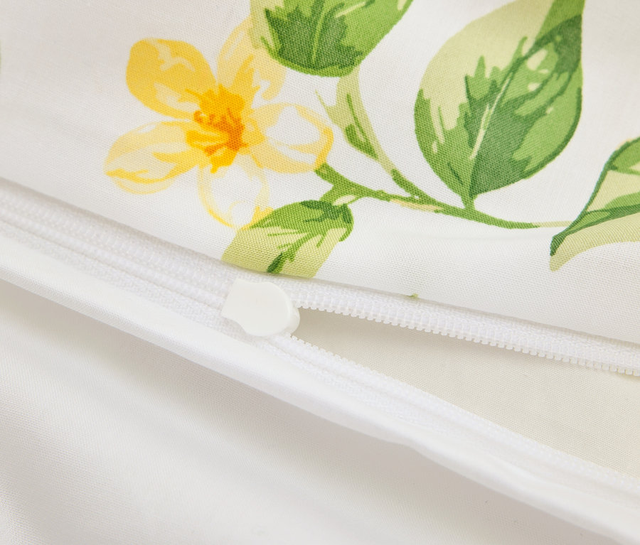 Nahaufnahme eines teilweise geöffneten weißen Kissens mit Reißverschluss und gelbem Blumenmuster.