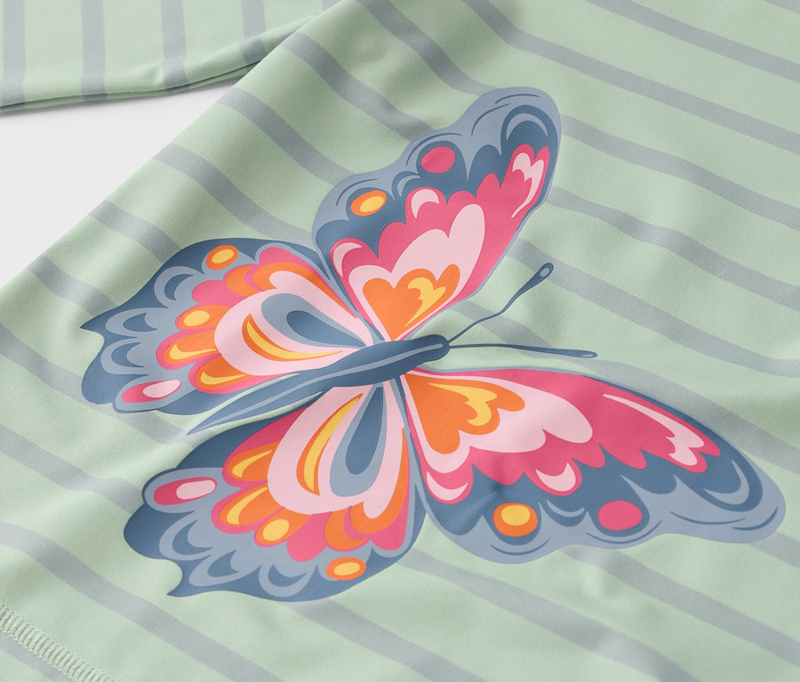 Nahaufnahme eines hellgrün gestreiften Stoffes mit einem großen Schmetterlingsaufdruck in Rosa, Orange und Blau.