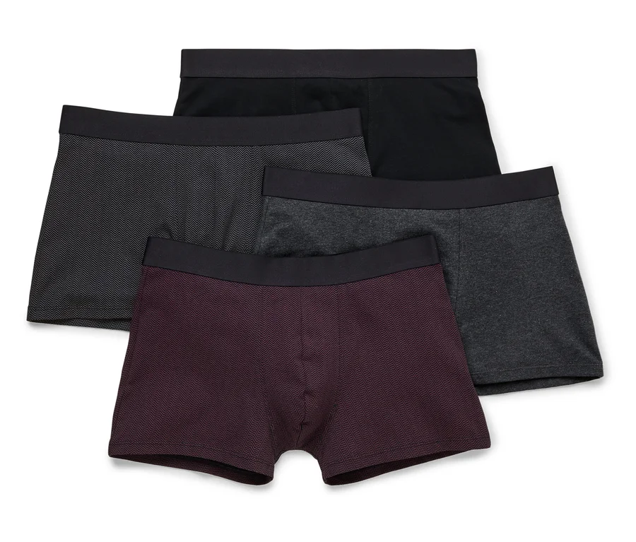 Vier Herren Boxershorts in Schwarz, Grau und Burgunder liegen übereinander.