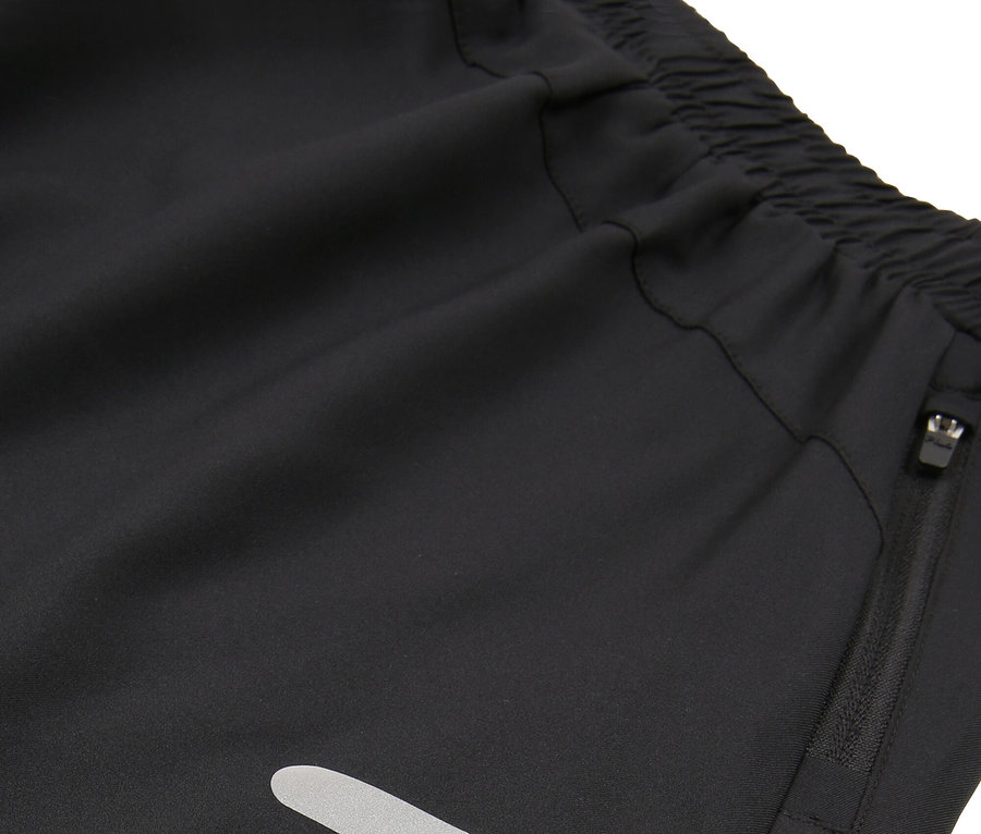 Nahaufnahme von schwarzen Shorts mit elastischem Bund, Reißverschlusstasche und reflektierenden Streifen.