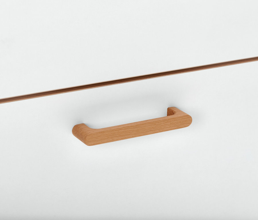 Detail einer weißen Kommode mit Furnierkante und Holzgriff.