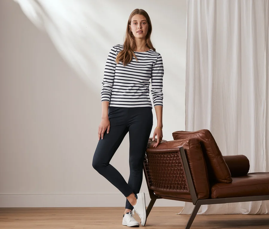 Eine Frau posiert an eine Ledercouch gelehnt und trägt eine Basic-Leggings aus Heavy-Jersey, dunkelblau.