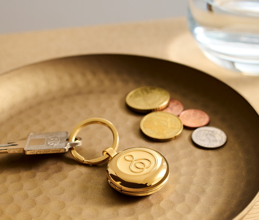 Goldener Pillendosen-Schlüsselbund liegt auf einem goldenen Tablett neben Schlüsseln und Münzen.