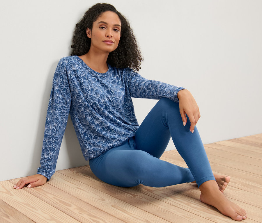 Frau sitzt im Leggings-Pyjama auf dem Boden.