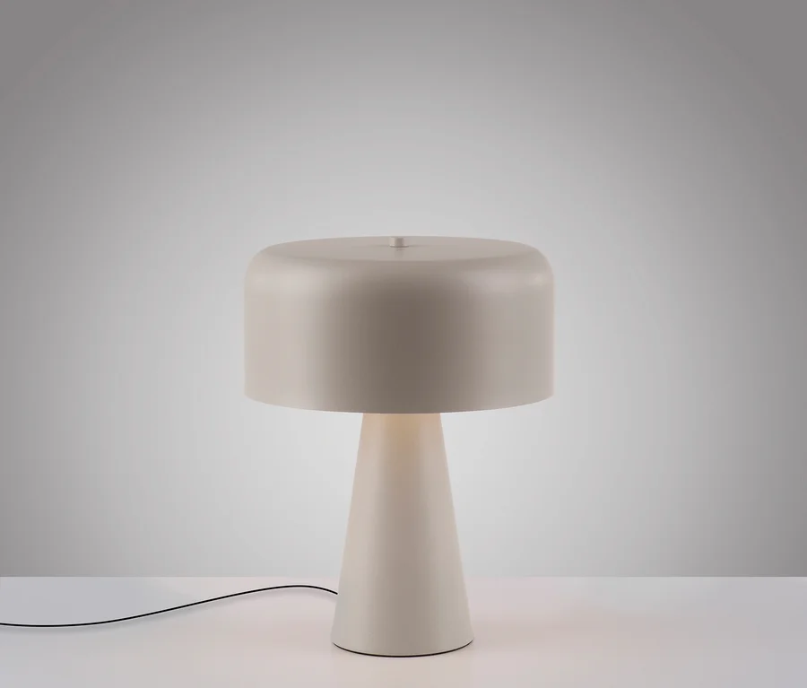 Beige Tischlampe mit rundem Schirm auf einem weißen Tisch.