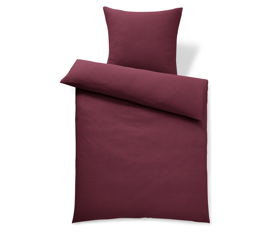 Weinrote Bettwäsche und Kissen auf weißem Hintergrund.