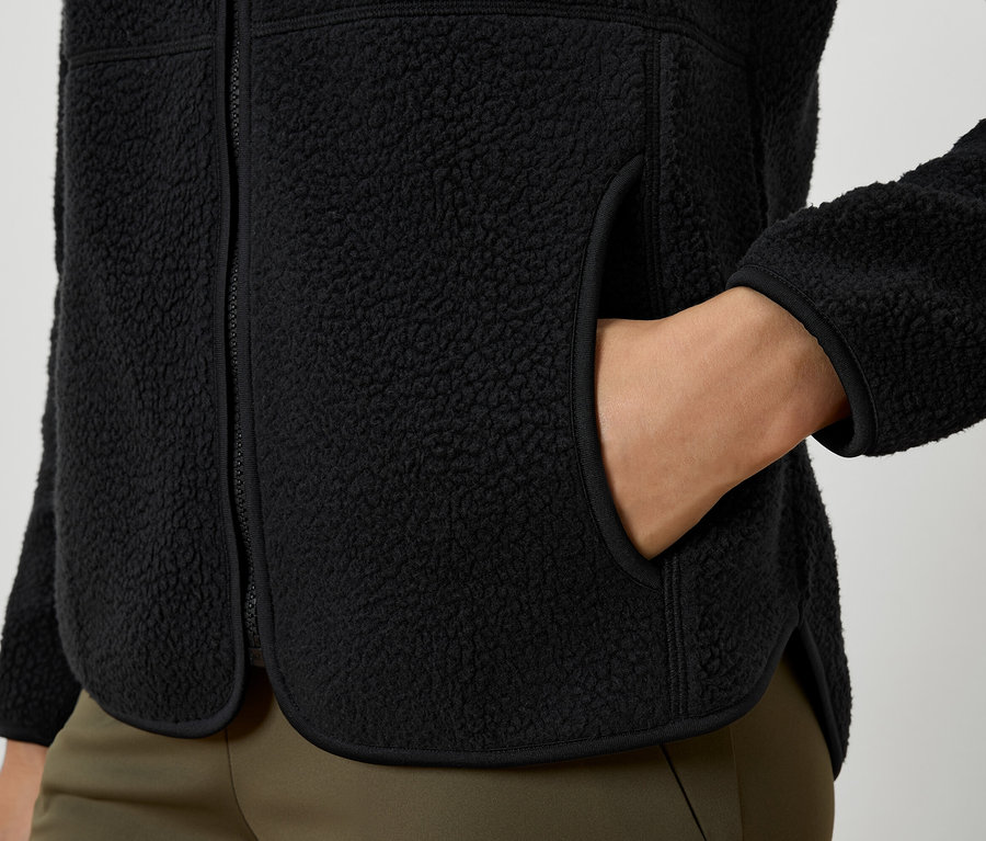 Detailaufnahme einer schwarzen Fleecejacke mit Hand in der Tasche.