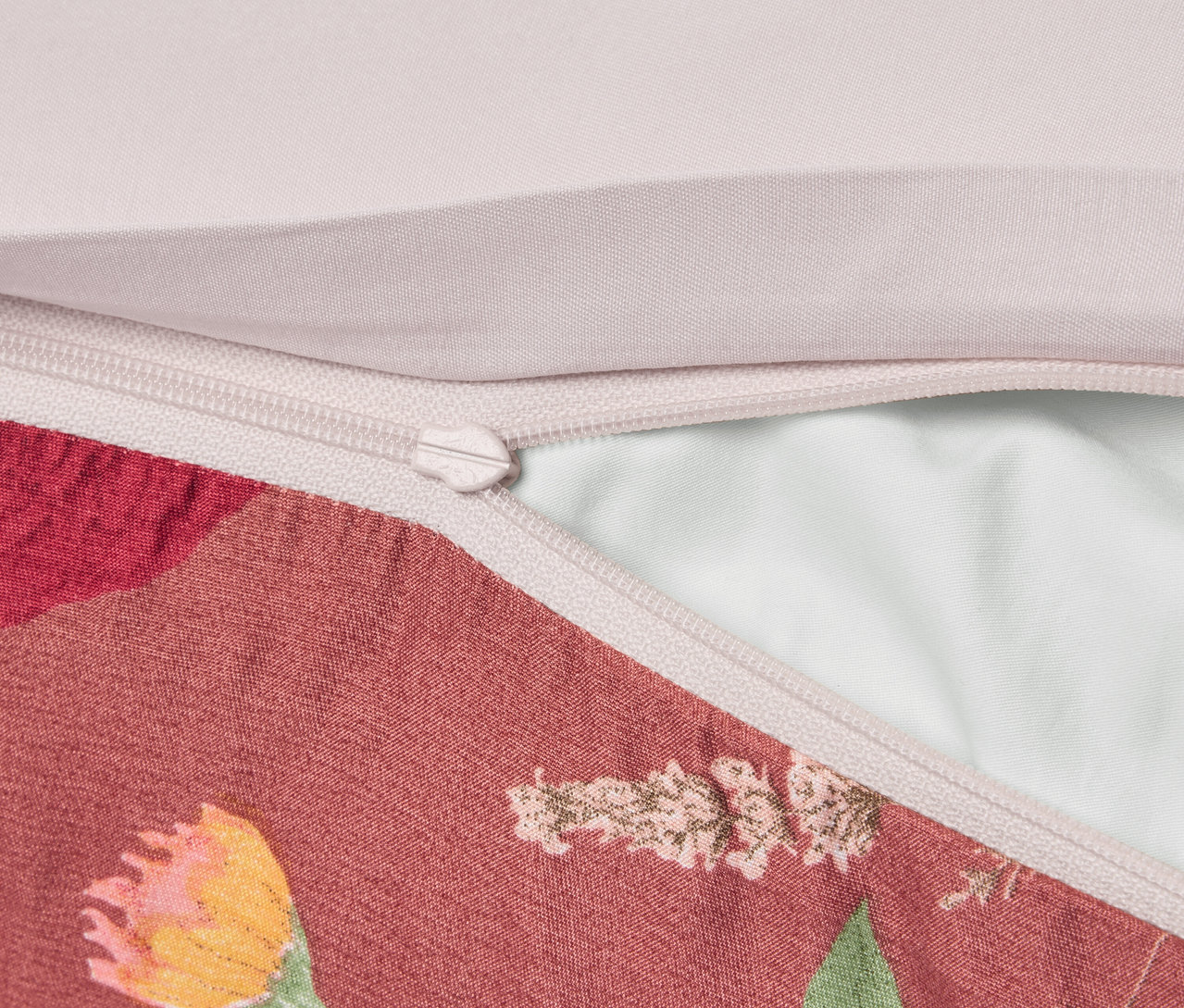 Detailaufnahme eines Kissenbezugs mit Blumenmuster und Reißverschluss.