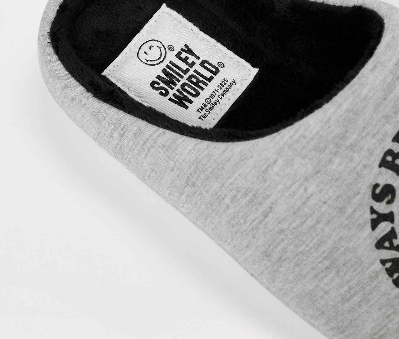 Detailansicht eines grauen SMILEYWORLD® Hausschuhs aus Stoff mit schwarzem Innenfutter und Logo-Etikett.