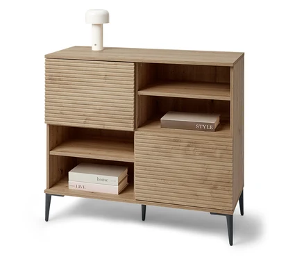 Ein Sideboard »REET« mit Lamellenoptik steht im Raum. Auf dem Sideboard steht eine kleine Lampe.