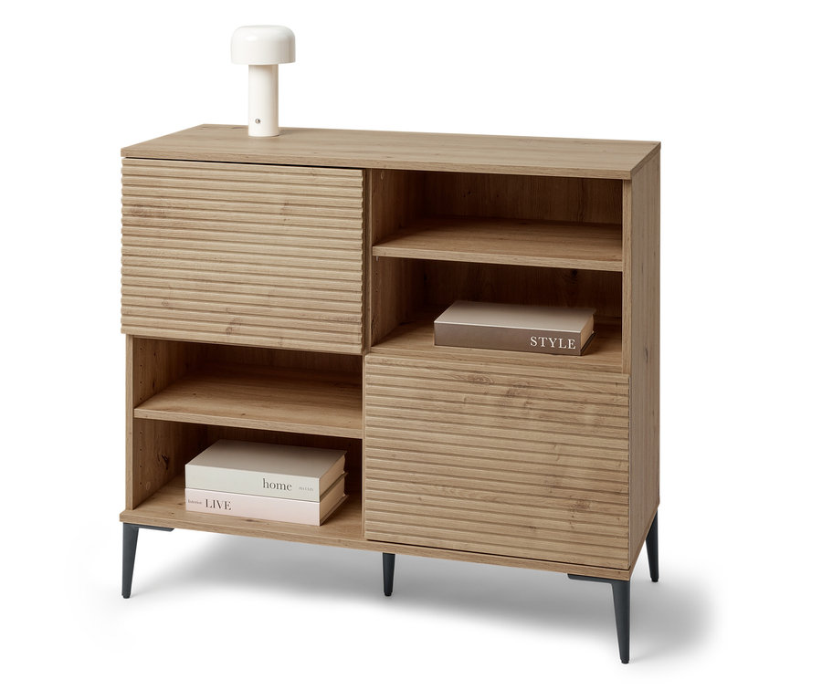 Ein Sideboard »REET« mit Lamellenoptik steht im Raum. Auf dem Sideboard steht eine kleine Lampe.