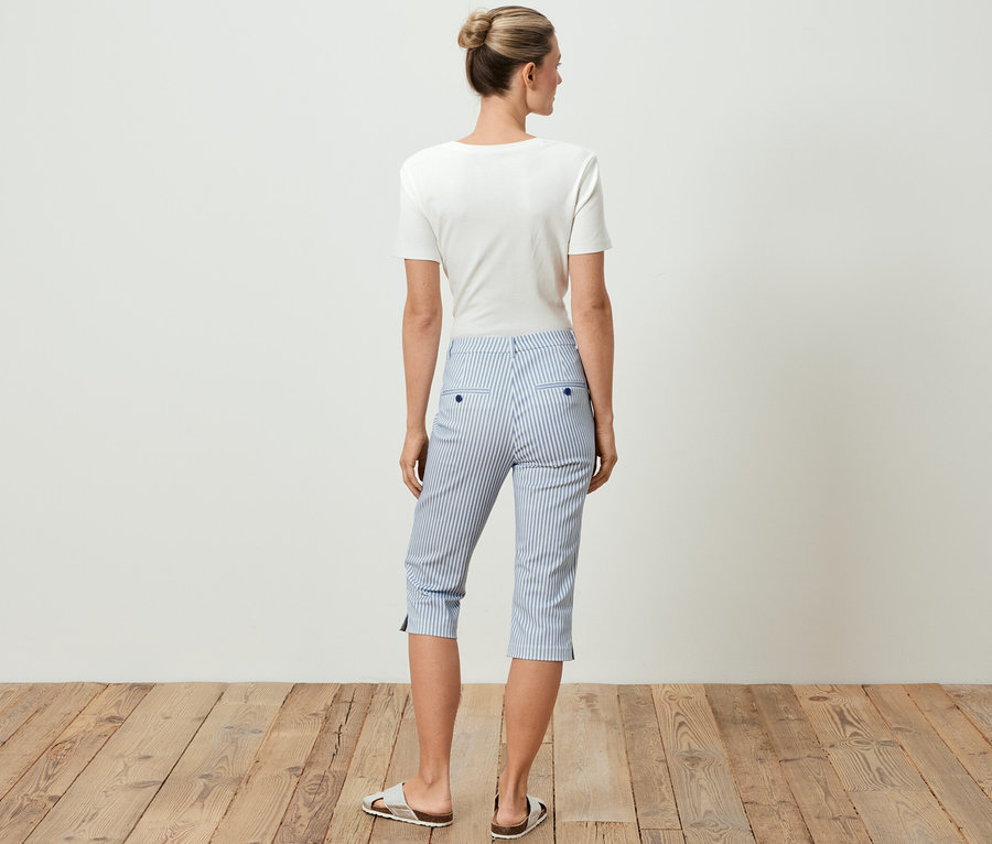 Frau von hinten trägt ein weißes T-Shirt und eine 3/4-Stretch-Twill-Hose mit blauen Streifen.