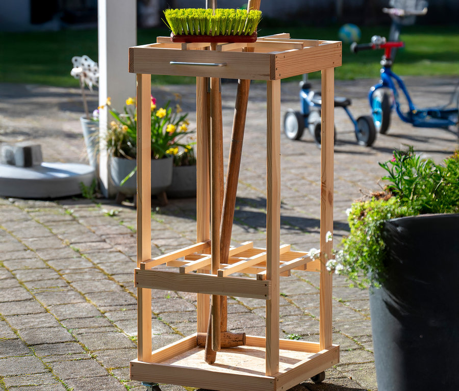 Holzwagen für Gartengeräte mit Besen, Rechen und Schaufel.