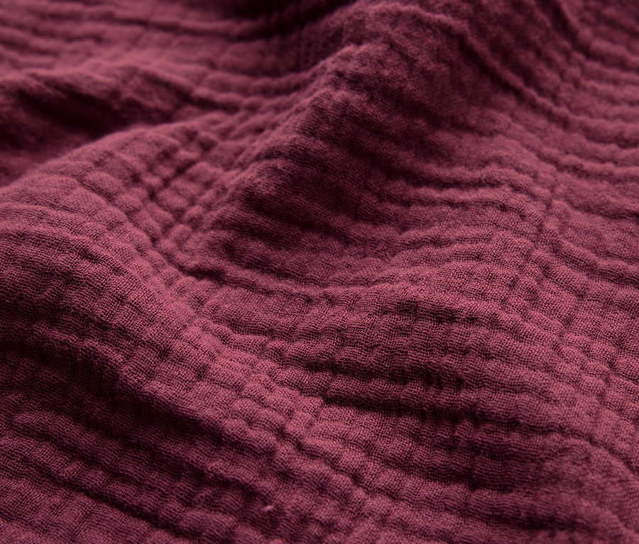 Nahaufnahme der Textur eines weinroten Stoffes.