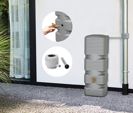 Grauer Regenwassertank mit Wasserhahn und Zubehör neben einem Fallrohr an einer weißen Wand.