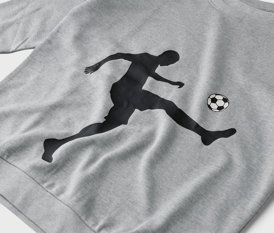 Auf einem grauen Pullover ist die Silhouette eines Fußballspielers abgebildet, der einen Ball tritt.