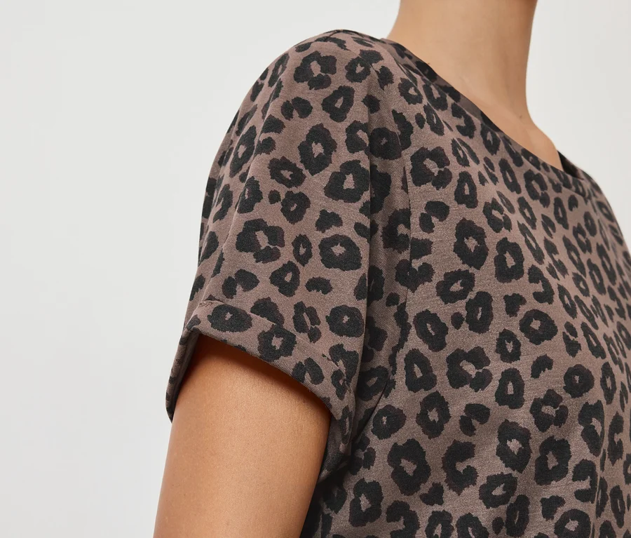 Nahaufnahme einer Person, die ein braunes T-Shirt mit schwarzem Leopardenmuster trägt.