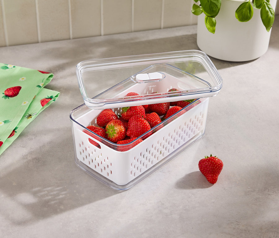 Erdbeeren in einem Frischhaltebehälter mit transparentem Deckel, daneben liegt ein Erdbeertuch.