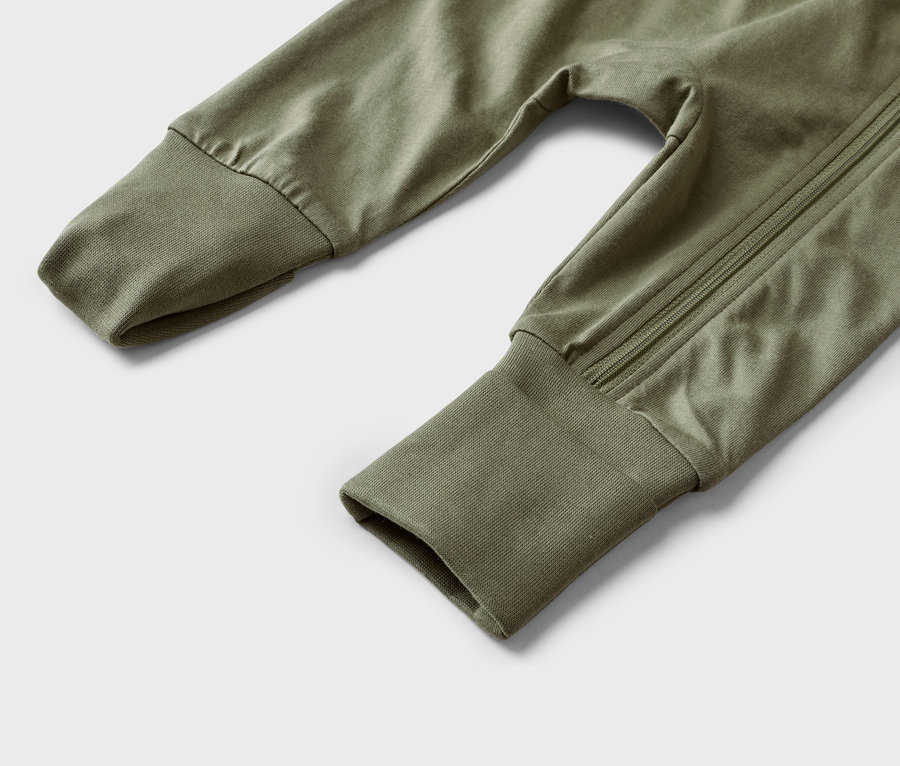 Nahaufnahme von olivgrünen Babyhosen mit Bündchen an den Ärmeln und einem Reißverschluss an der Seite.