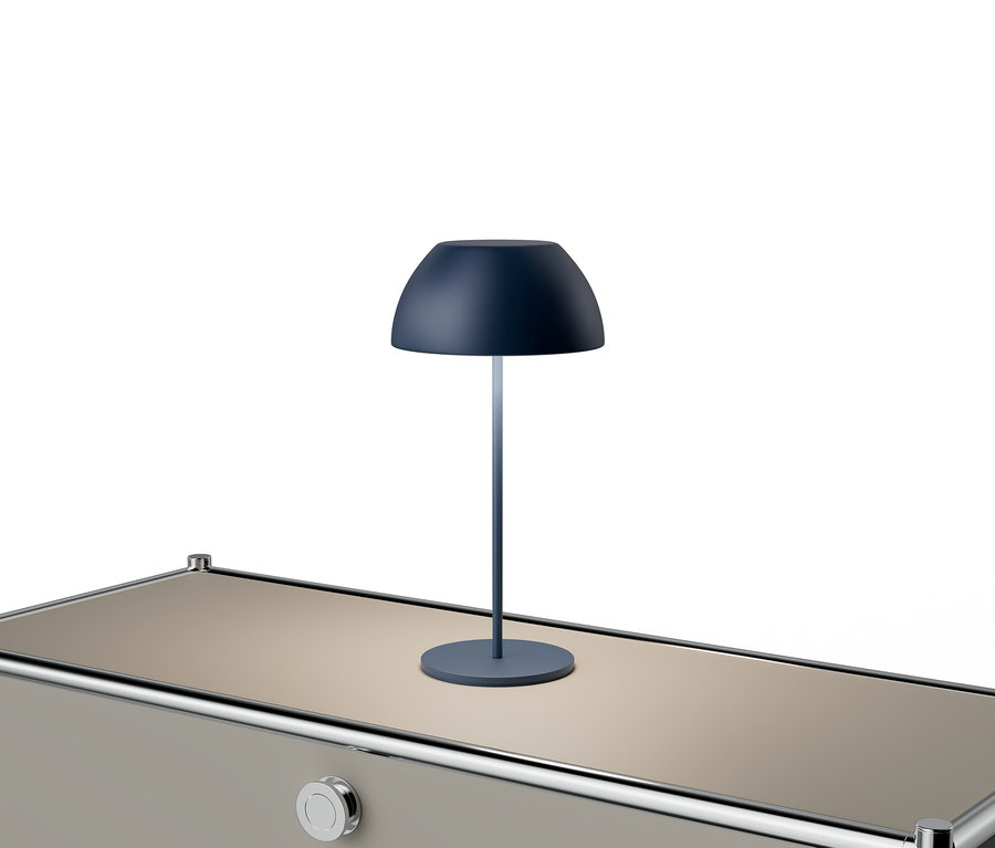 Eine blaue Lampe steht auf einem beigen Tisch mit silbernen Akzenten.