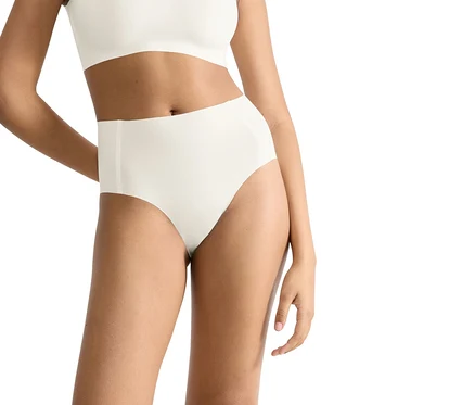 Person trägt weiße sloggi ZERO Feel 2.0 High Waist Unterhose und passendes BH-Top. Die Hände sind hinter dem Rücken.