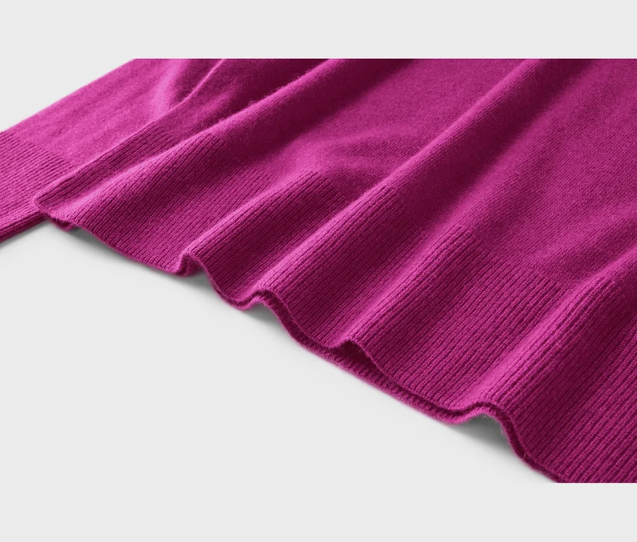 Nahaufnahme eines fuchsiafarbenen Pullovers mit sichtbaren Falten und Rippstrickbündchen am Saum und Ärmel.