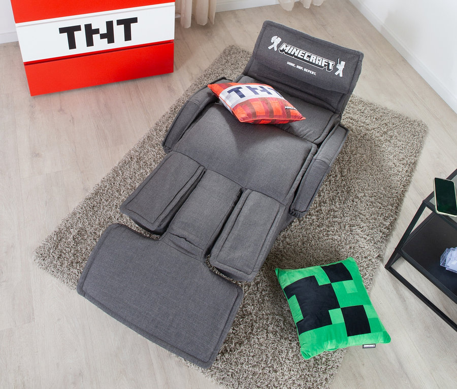 Grauer roba Minecraft Loungesessel mit Beinen und Armlehne auf Teppich, neben rotem Nachttisch mit TNT-Motiv.