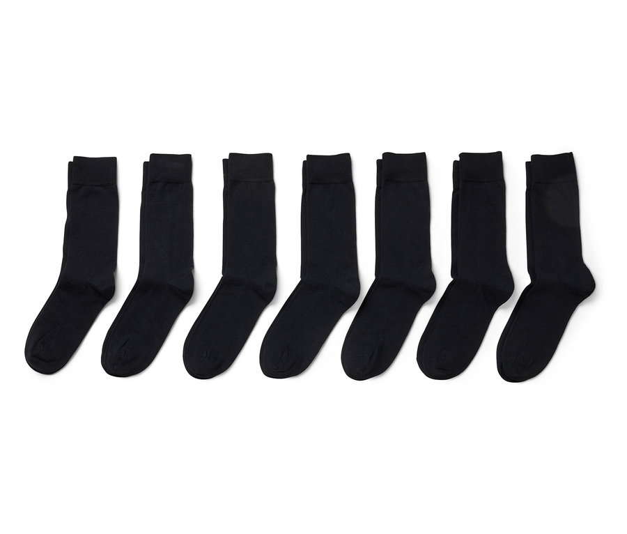 Sieben Paar schwarze Socken, die in einer Reihe auf einem weißen Hintergrund angeordnet sind.