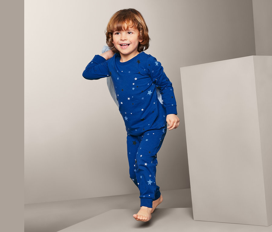 Junge trägt einen blauen Pyjama mit Sternenmuster.