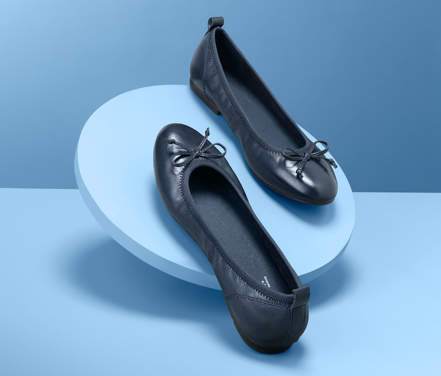 Zwei dunkelblaue Leder-Ballerinas auf hellblauem Hintergrund.